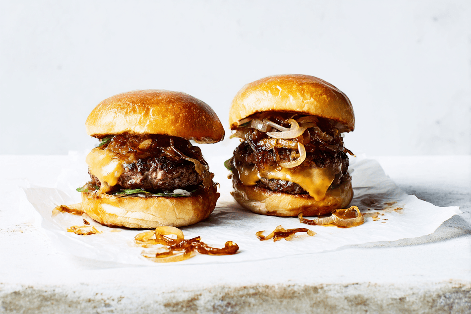 Beef cheeseburgers with melted cheese and caramelised onions in toasted buns